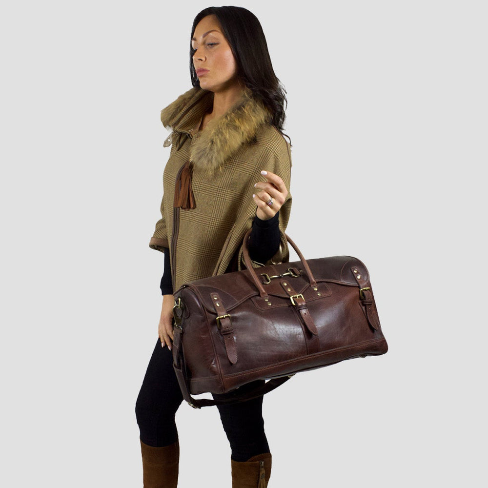 Woman holding a brown leather bag against a plain background