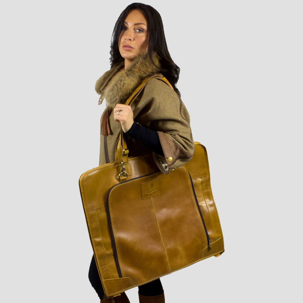 Woman holding a large brown leather bag against a white background