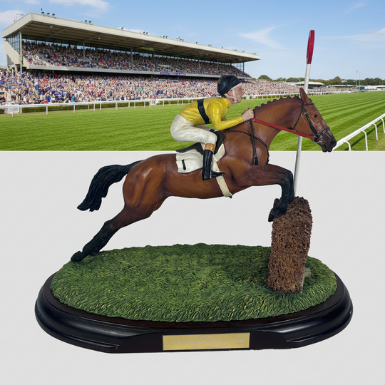 A detailed equestrian figurine depicting a jockey in a yellow and white uniform riding a brown horse over a jump on a textured green grass base, mounted on a black oval wooden plaque.