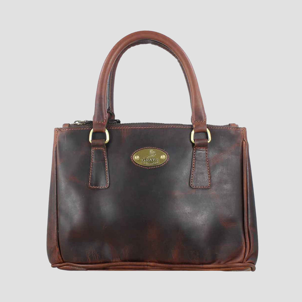 Brown leather handbag with gold accents on a light gray background