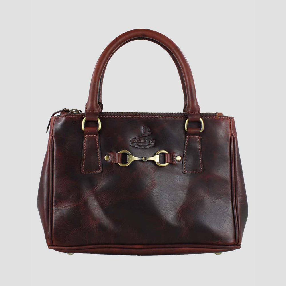 Brown leather handbag with gold hardware on a light gray background