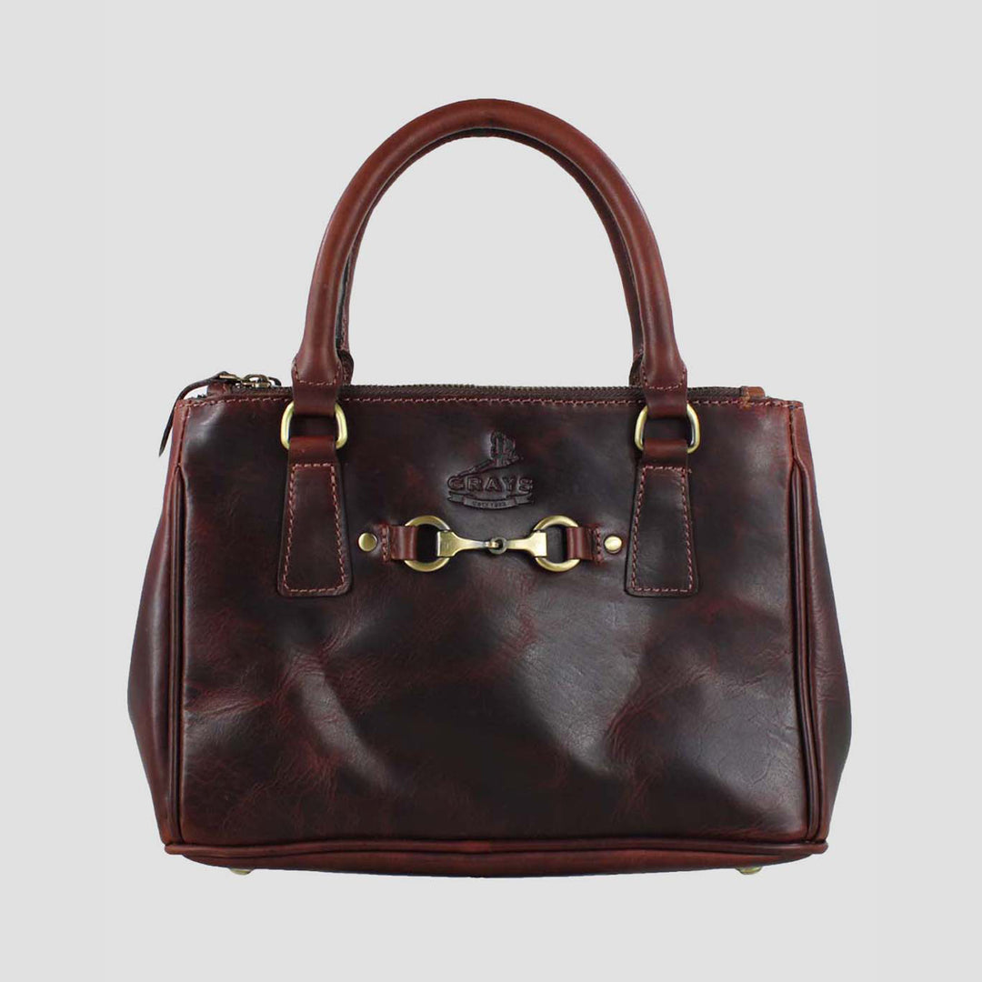 Brown leather handbag with gold hardware on a light gray background