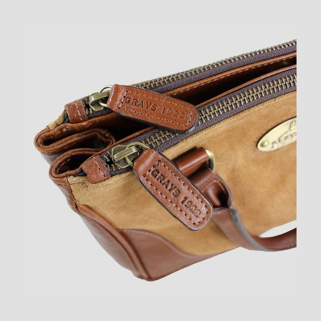 Brown leather bag with multiple zippers on a light gray background